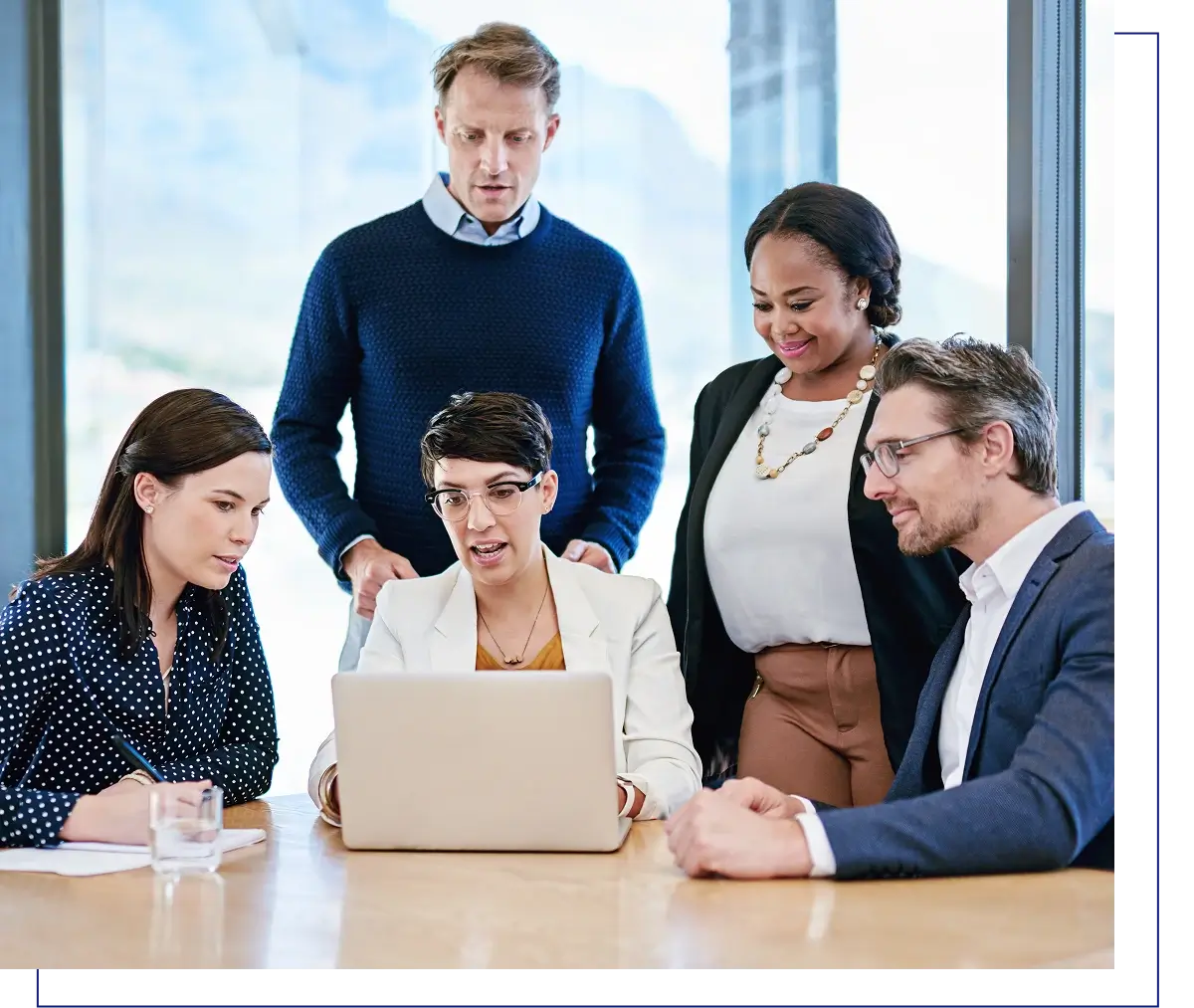 Team collaborating around a laptop at table.