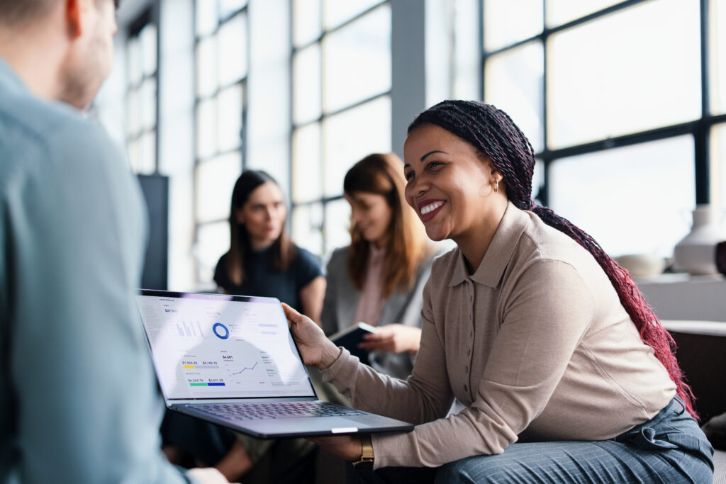 Smiling woman showing laptop analytics to colleague
