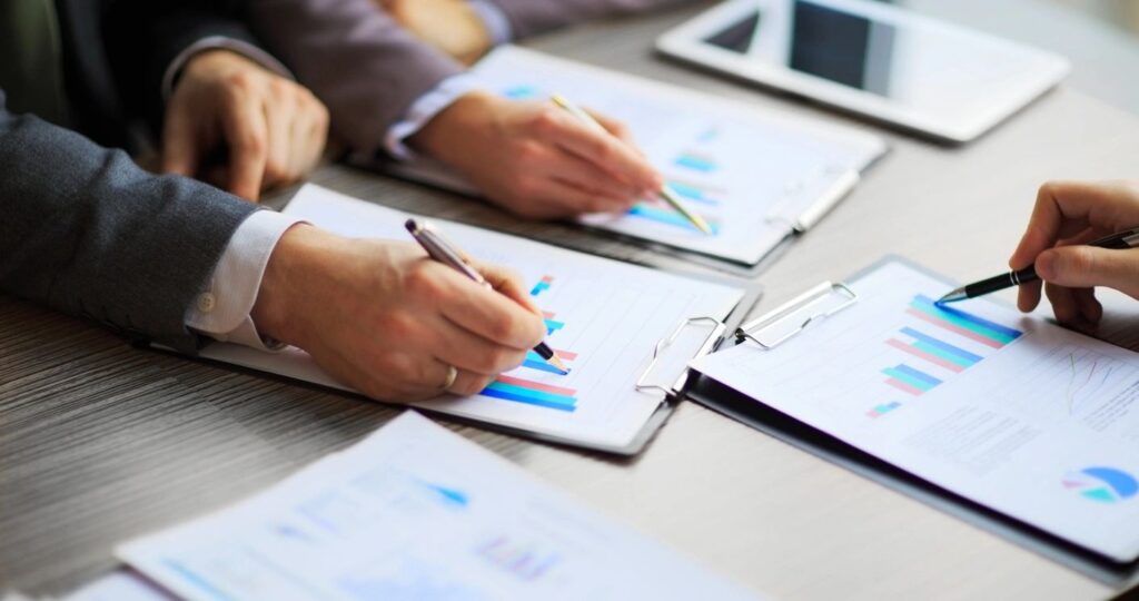 Business team reviewing financial graphs on clipboards