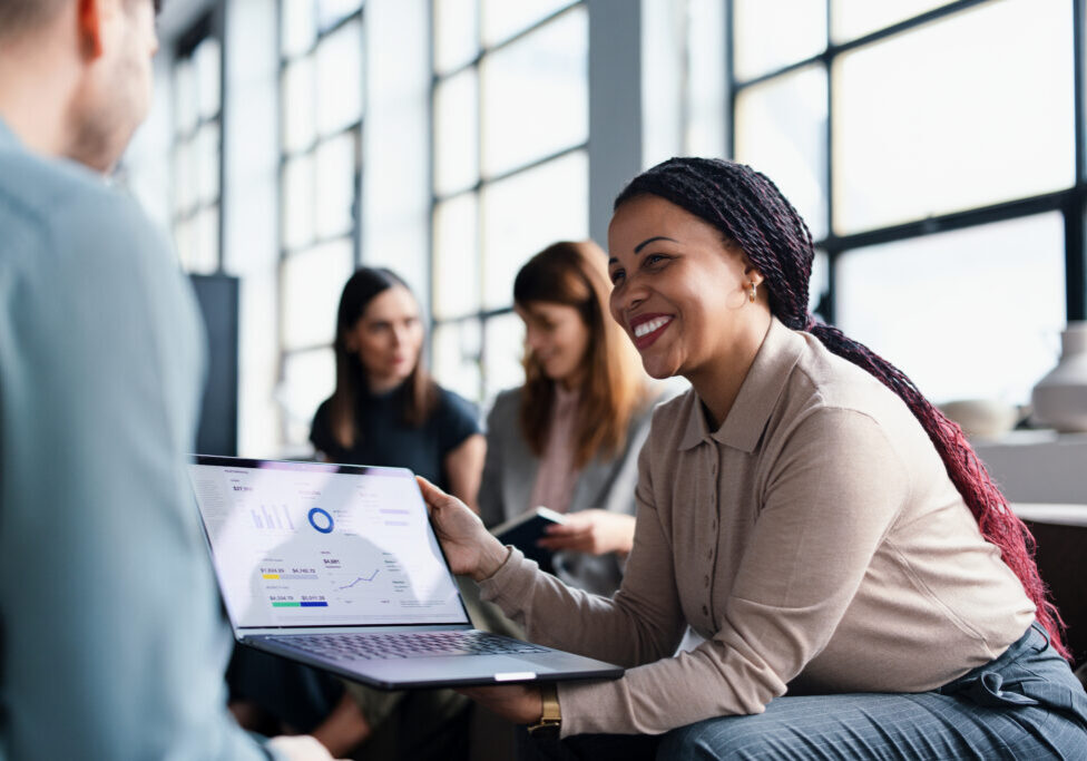 Smiling woman showing laptop analytics to colleague