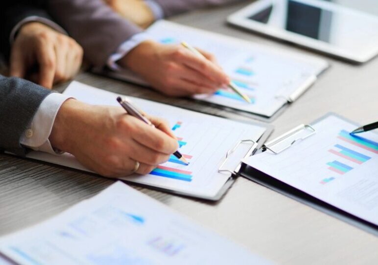 Business team reviewing financial graphs on clipboards